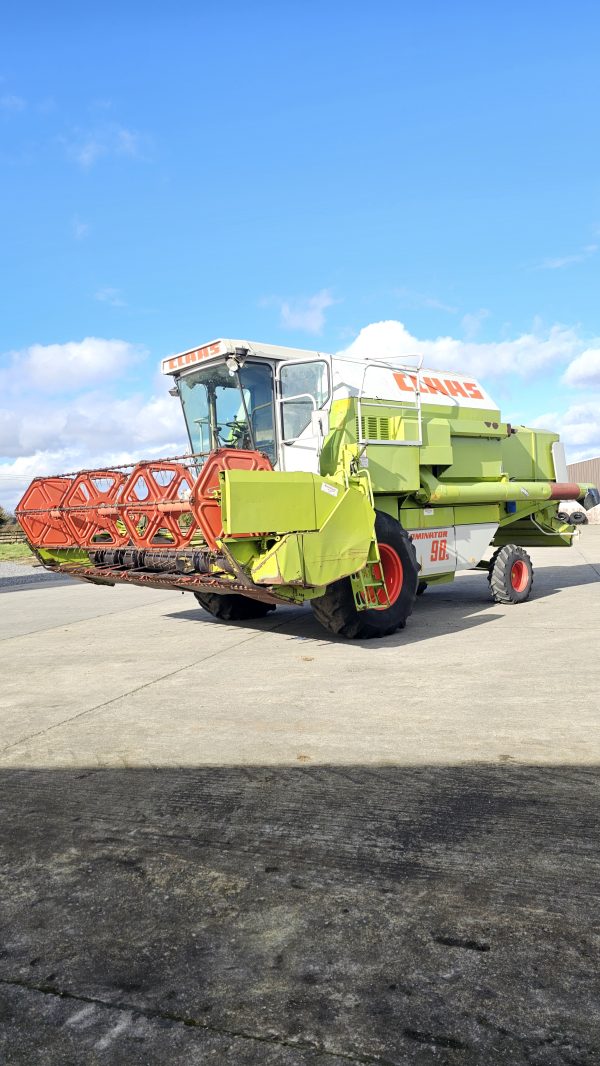 The front-left side view of the Claas Dominator 98S combine harvester, highlighting its header, front wheels, and body design.
