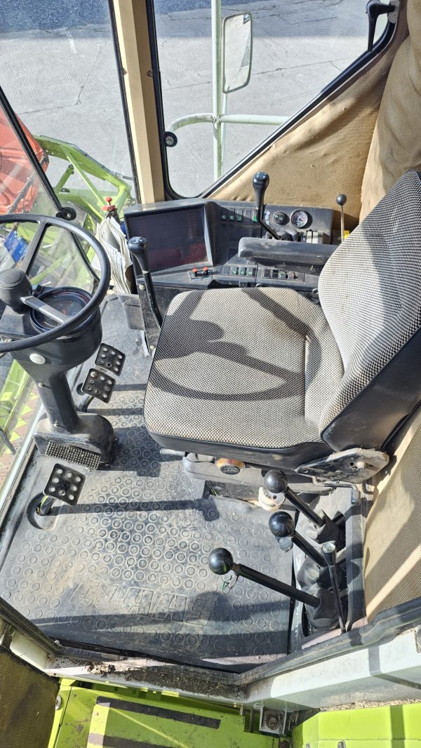 Inside view of the Claas Dominator 98S cabin, showcasing the control panel, steering wheel, and operator seat.