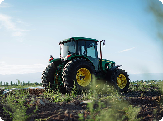 A green tractor working in the field, engaged in agricultural tasks.