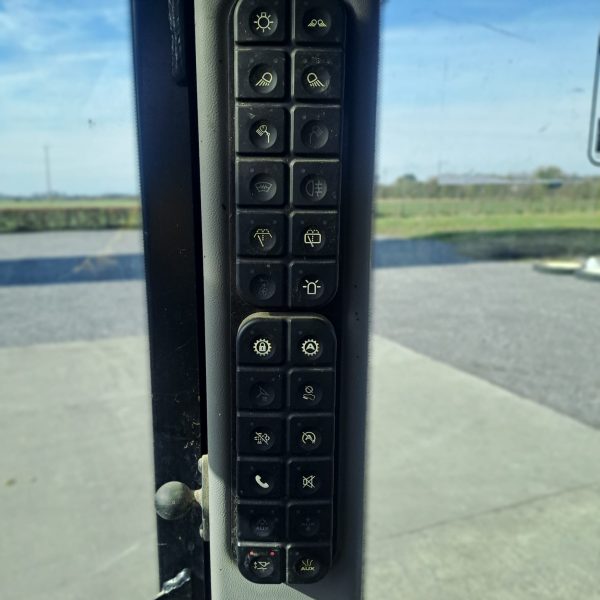 Close-up of the JCB TM 320S cabin controls, featuring multiple buttons including headlight, phone, and mute buttons for easy access.