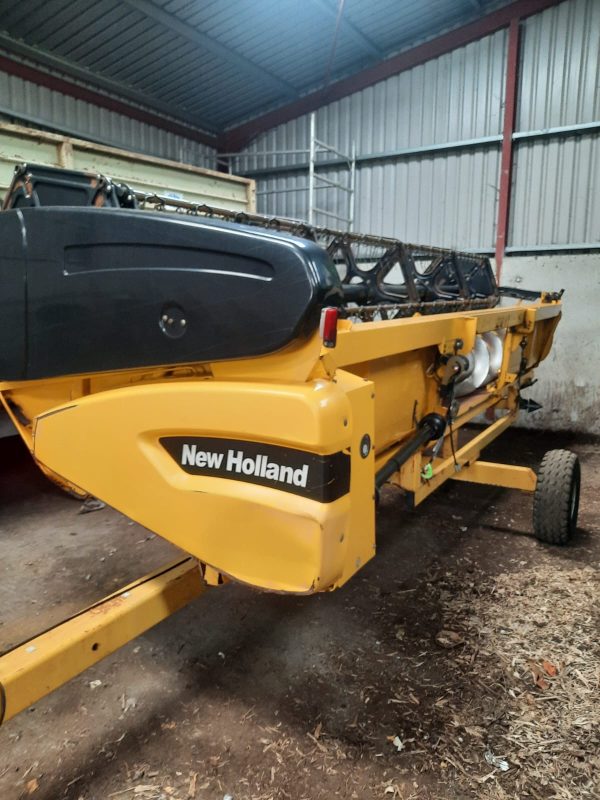 Front side view of a New Holland harvester attachment with cutting equipment.
