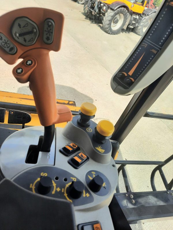 Inside view of the New Holland Combine CS 640 cabin, displaying the buttons, controls, and gear stick for efficient operation.