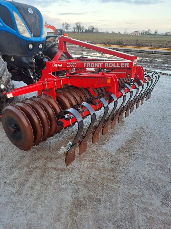 Side view of the Front Press HI VA attached to a blue tractor, showcasing its robust construction for agricultural use.