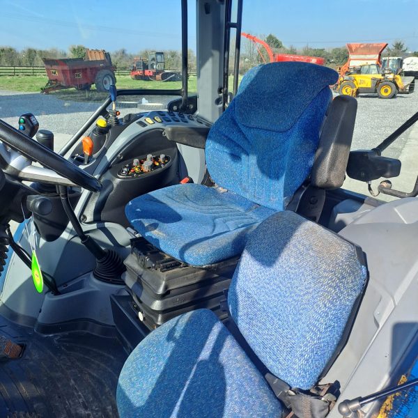 Interior view of a tractor cabin with blue seats, showcasing the ergonomic design and controls for farming operations.