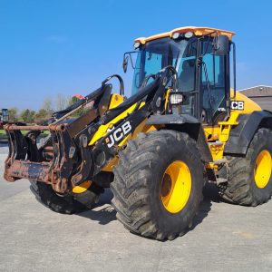 Side view of a JCB yellow tractor, with the front pointing to the southwest, showcasing its design and agricultural features.