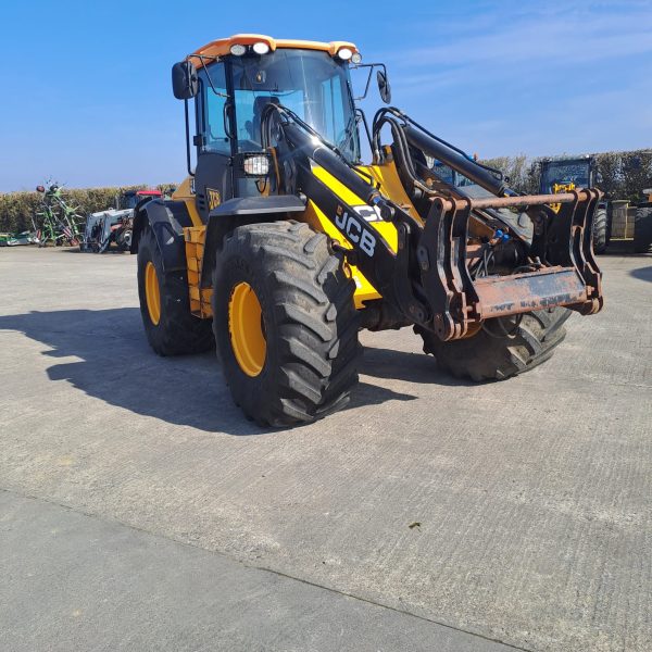 Front view of a JCB yellow tractor, with the front facing southeast, showcasing its powerful design and agricultural capabilities.