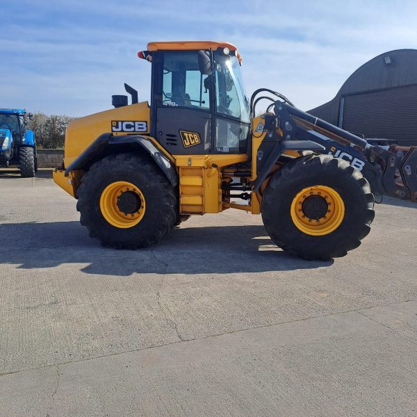 Side view of a JCB yellow tractor, with the front facing to the right, showcasing its design and agricultural machinery features.