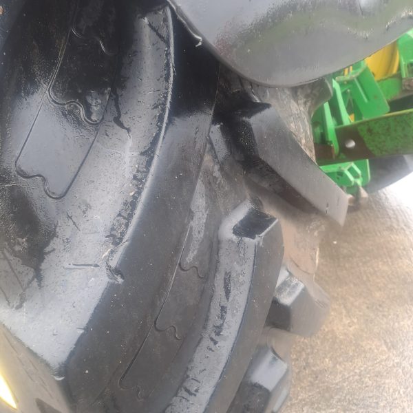 Close-up of a John Deere tractor tire, showcasing the tread pattern and robust design for agricultural machinery.