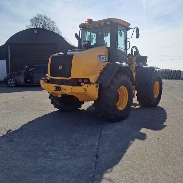 Back diagonal view of a JCB yellow tractor, with the rear pointed to the southwest, showcasing its design and agricultural machinery features.