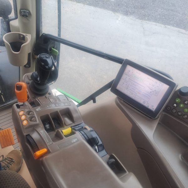 Inside view of a tractor cabin showing the digital display tablet and nearby gears, highlighting the advanced technology and controls.