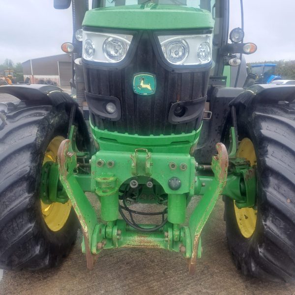 Close-up front view of a John Deere tractor, highlighting its grille, headlights, and agricultural machinery design.