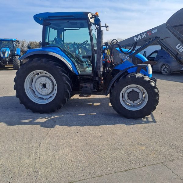 Side view of a blue U8 MX tractor, showcasing its design and machinery in an agricultural setting.