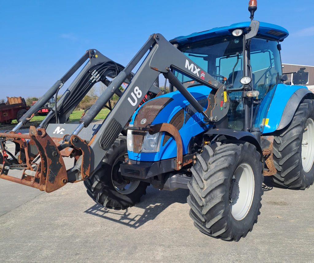 Blue U8 MX tractor in a field, with a bright blue sky in the background, symbolizing agricultural machinery and farming operations.