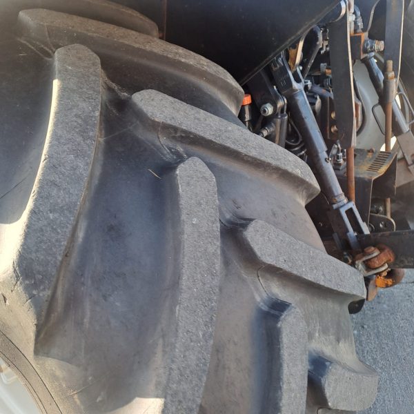 Close-up of a tractor wheel with part of the engine visible in the background, showcasing the machinery and design.